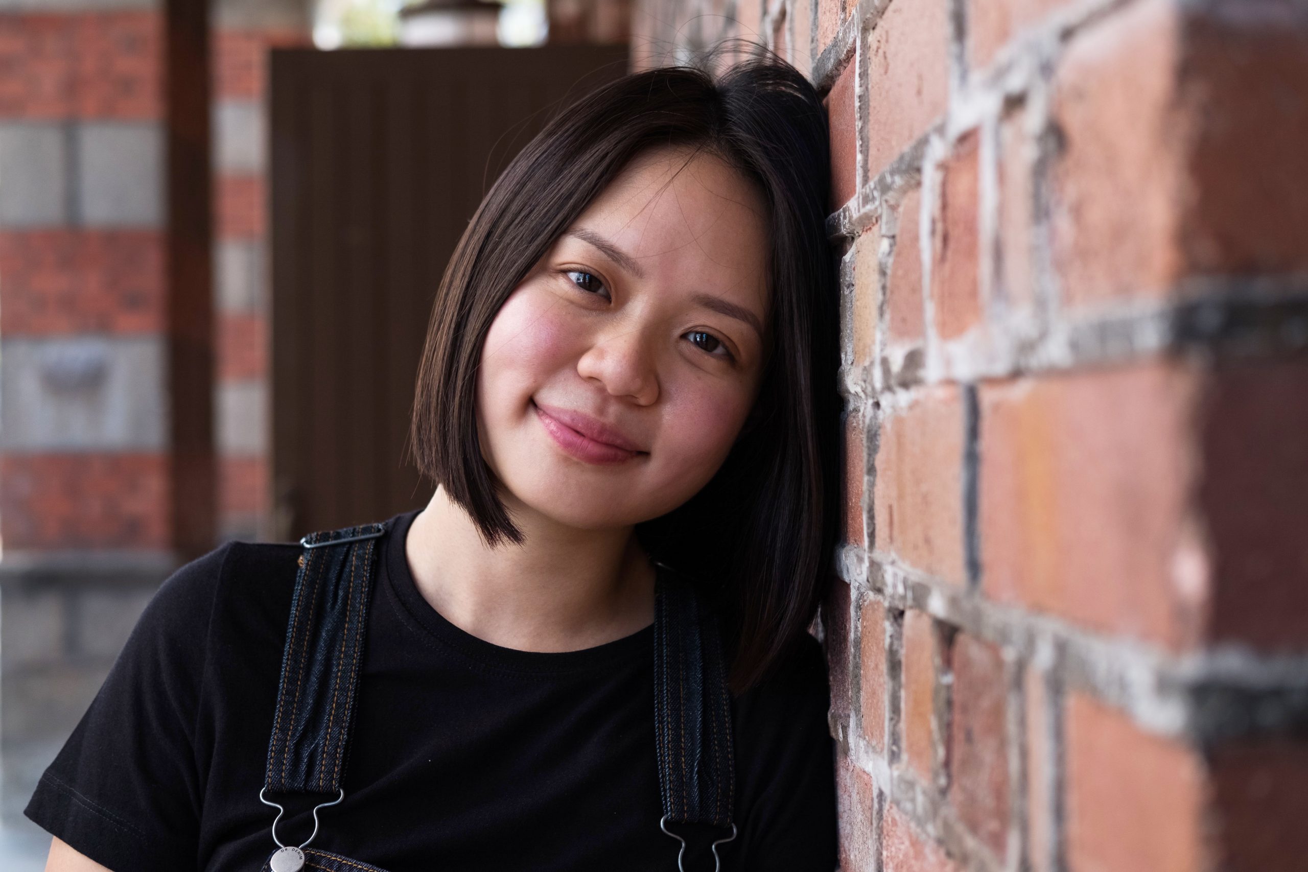 Chinese student leaning against brick wall